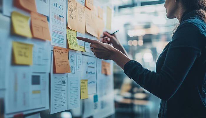 Worker mapping out ideas on board with paper and post-it notes