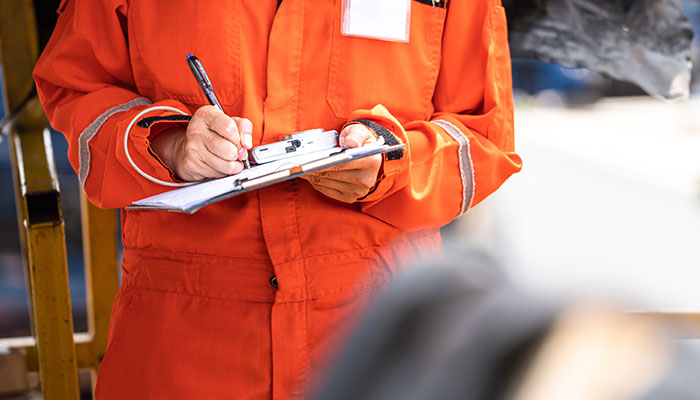 Construction worker writing on clipboard