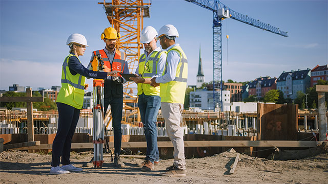 Construction Site Experts discussing Management Plans on Tablet