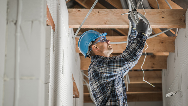 Electrical worker fixing wiring in roof