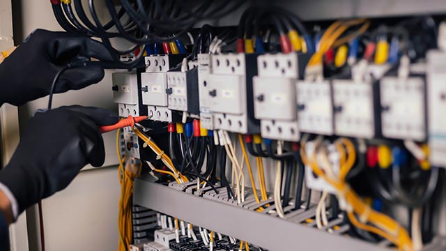 Electrician checking voltage on fuse box