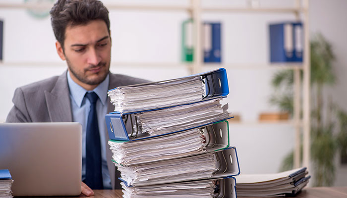 Employee inundated with a pile of folders