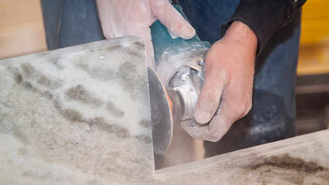 Man making vertical cut with electric hand saw during align marble kitchen countertop at construction site. marble cutting with grinding cutter