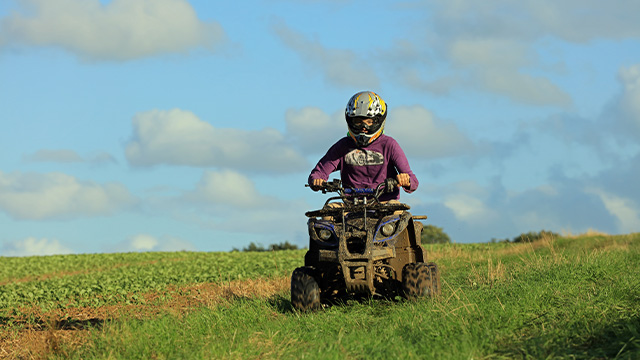 Young teenage boy riding a quad bike in the countryside.