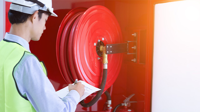 Worker inspecting the fire hose and ticking off compliance