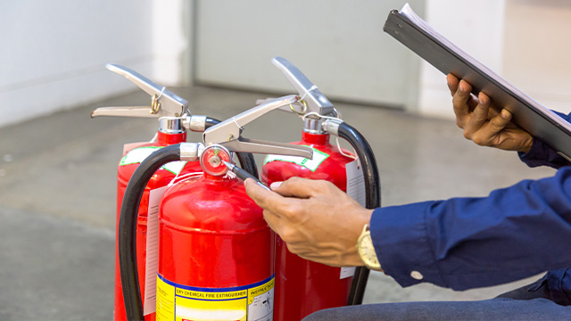 Worker checking the dates on the fire extinguishers to ensure they are in date incase of a fire