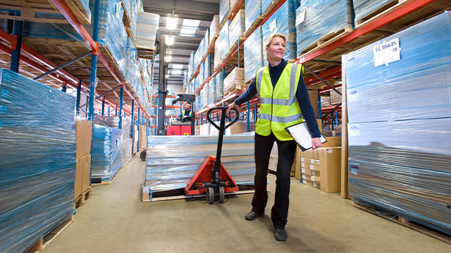 female factory worker using a trolley to move heavy pallets 