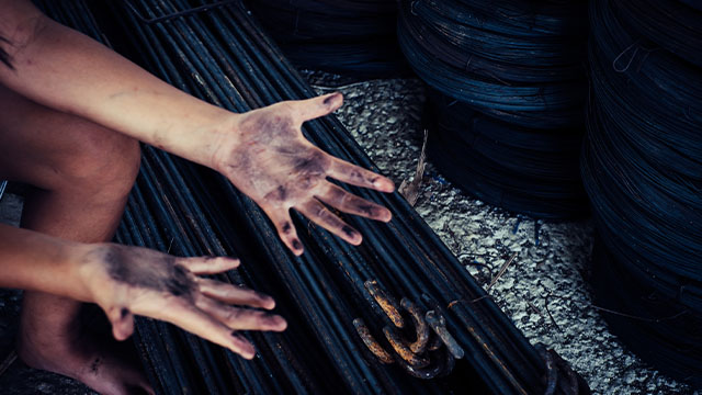 Hands and feet of a child worker covered in dirt 