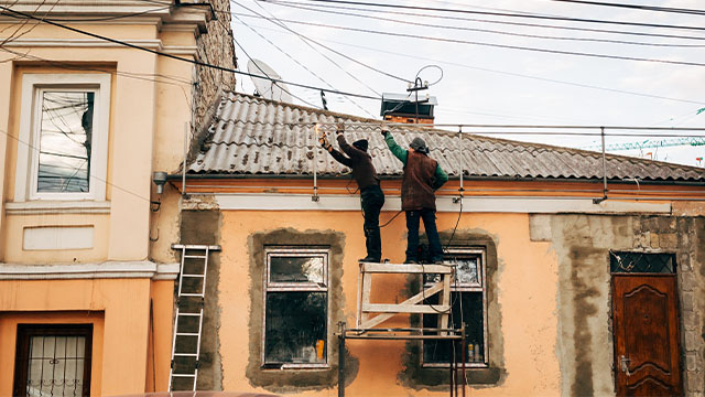 Two male workers on unsafe scaffolding 
