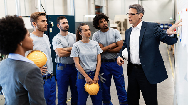 Male boss pointing to board showing the risks to all factory workers