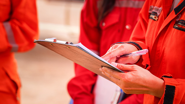 Three workers discussing the risks associated with the job using a risk assessment