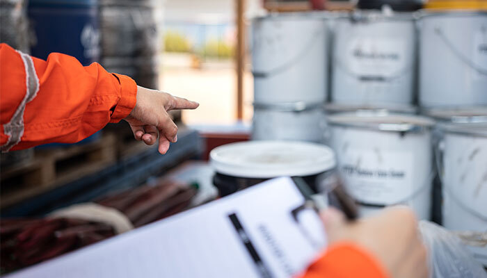 Safety officer pointing at chemicals stored in storage containers