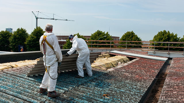 Two workers wearing personal protective equipment to remove asbestos