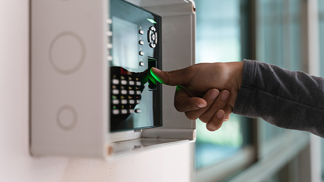 A worker using their thumbprint to check in to their shift and get into the building