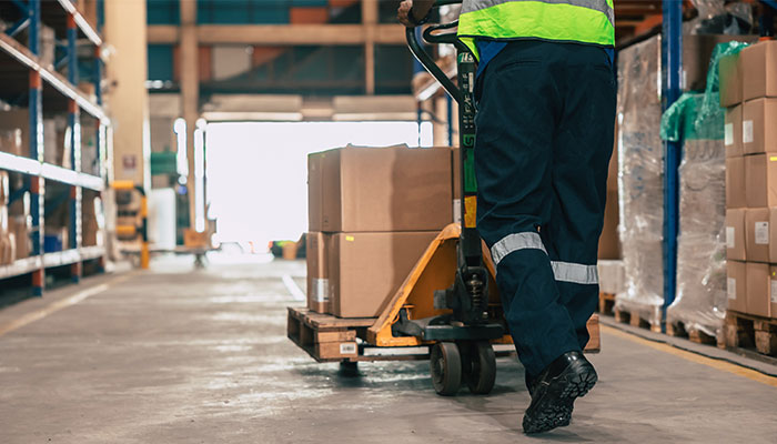 Worker transporting goods in warehouse